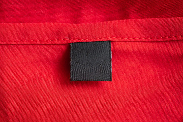 Blank black laundry care clothing label on red color fabric texture