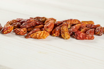 Lot of whole dry red chili pepper peperoncino on white wood