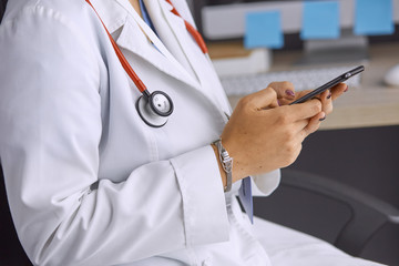 female doctor between patients in the office talking on the pho