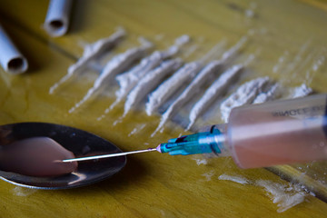 syringe and Indonesia rupiah and Cocaine ready for uses on wooden table. Cocaine Drug Addiction...