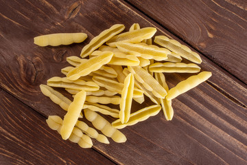 Lot of whole uncooked pasta cavatelli heap flatlay on brown wood