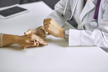 Woman doctor calms patient and holds hand