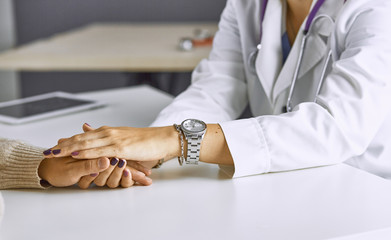 Woman doctor calms patient and holds hand