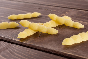 Lot of whole uncooked pasta cavatelli on brown wood
