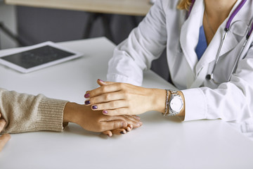 Woman doctor calms patient and holds hand