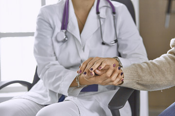 Woman doctor calms patient and holds hand