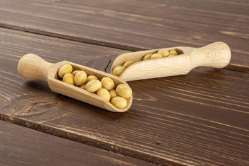 Lot of whole raw yellow soya bean in two scoops on brown wood