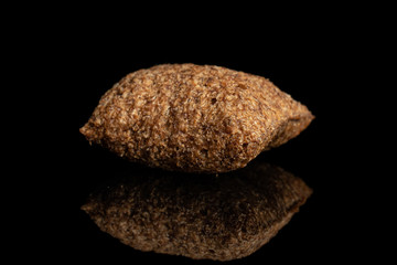 One whole crispy brown cereal pillow isolated on black glass