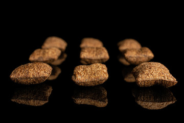 Group of nine whole crispy brown cereal pillow isolated on black glass
