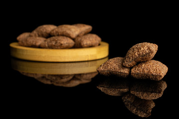 Lot of whole crispy brown cereal pillow on bamboo coaster isolated on black glass