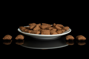 Lot of whole crispy brown cereal pillow on white ceramic plate isolated on black glass