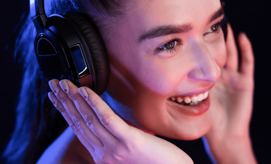 Young woman enjoying music in headset, posing in studio