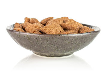 Lot of whole crispy brown cereal pillow in dark ceramic bowl isolated on white background