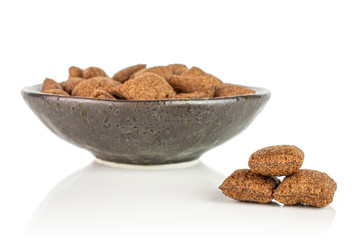 Lot of whole crispy brown cereal pillow in dark ceramic bowl isolated on white background