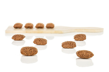 Lot of whole crispy brown cereal pillow on small wooden cutting board isolated on white background