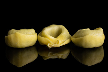 Group of three whole fresh yellow spinach filled tortelloni isolated on black glass