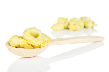 Lot of whole fresh yellow spinach filled tortelloni in a wooden spoon isolated on white background