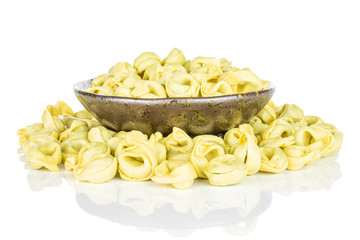 Lot of whole fresh yellow spinach filled tortelloni in dark ceramic bowl isolated on white background