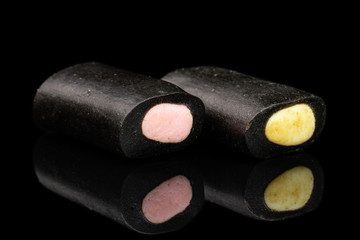 Group of two whole sweet black liquorice candy isolated on black glass