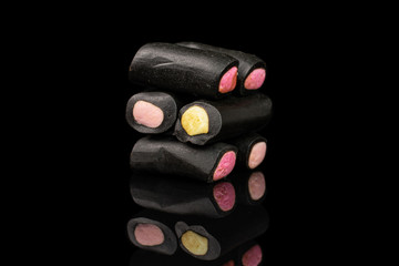 Group of six whole sweet black liquorice candy isolated on black glass