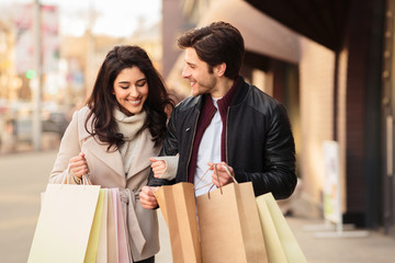 Young shopaholics looking into shopping bags outdoors