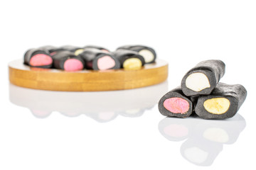 Lot of whole sweet black liquorice candy on bamboo coaster isolated on white background