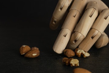 Lot of whole brown almond nut heap with wooden arm isolated on grey stone