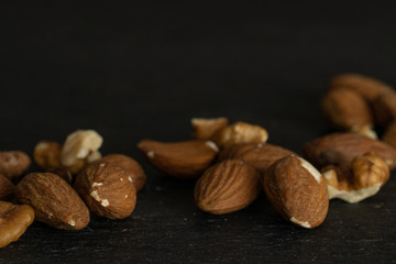 Lot of whole brown almond nut isolated on grey stone