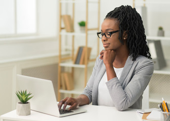 Pensive Afro Businesswoman Typing On Laptop In Modern Office
