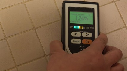 Man using moisture meter for house inspection and measuring moisture in bathroom. 