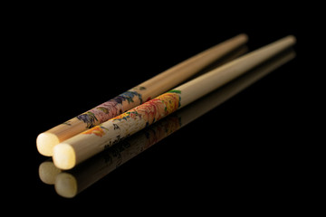Group of two whole asian brown chopsticks isolated on black glass