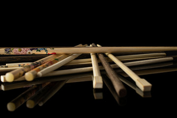 Lot of whole colorful asian brown chopsticks heap isolated on black glass