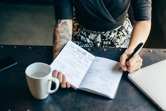 Close up view of young businesswoman writing notes in diary