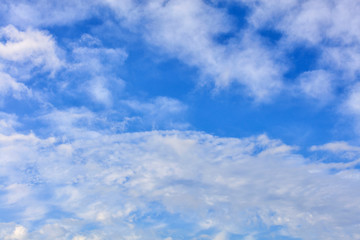 Fototapeta premium White lush and cheerful clouds float in the bright saturated blue sky.