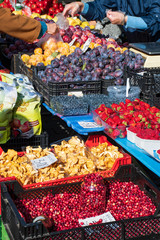Various berries, strawberries, raspberries, blueberries, prunes and mushrooms on the grocery stand on the street food market. Summer fruits. Healthy food with vitamin. Colorful. Vertical