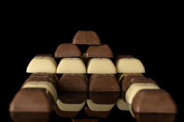 Lot of whole arranged fresh chocolate piece heap isolated on black glass