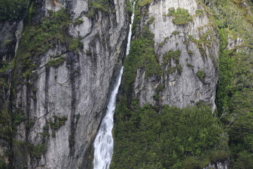 wąskie i wysokie wodospady los amigos w Ushuaia spływające po wysokich stromych ścianach skalnych pokrytych fragmentarycznie roślinnością 