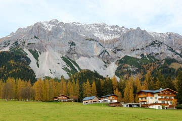 Autumn landscape with village at the foot of the alps mountains