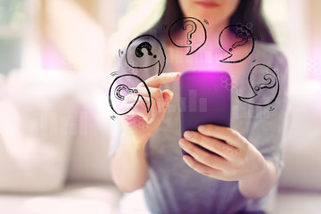Question marks with speech bubbles with woman using her smartphone in a living room