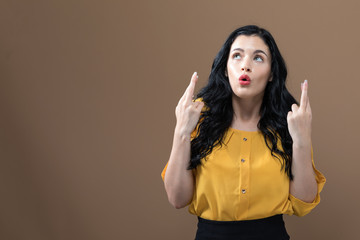 Young woman crossing her fingers and wishing for good luck