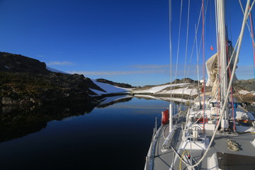 widok z jachtu na spokojne zimne wody oraz górzyste i ośnieżone wybrzżeże antarktydy