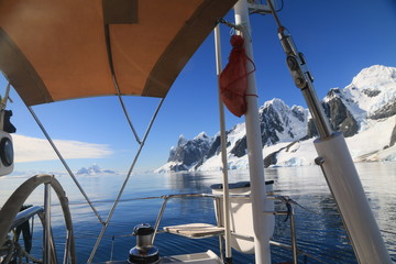 widok z jachtu na zimmne wody antarktydy i ośnieżone góry w słoneczny dzień
