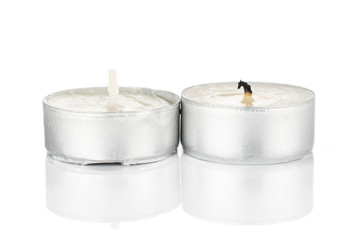 Group of two whole waxy white tea candle one burnt isolated on white background