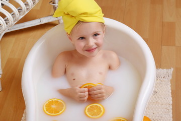 4 years old girl bathes in milk with oranges