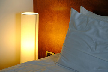 High cylinder shape of lamp, glowing beside the bed
