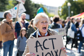 Senior with placard and poster on global strike for climate change, shouting.