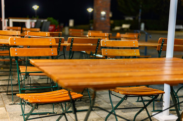 View to a group of wooden patio furniture on the terrace of a restaurant.
