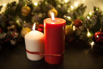 Christmas candles on the background of branches of a Christmas tree and glowing garlands