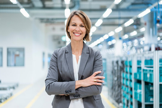 Portrait of a smiling businesswoman in a modern factory - Powered by Adobe