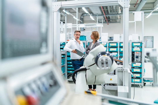 Businesswoman and manwith tablet talking in a modern factory